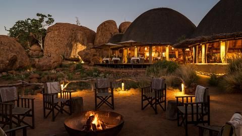 Chiwani Safari Camps' Mowani Mountain Camp Firepit and Dining Area - View across the firepit to the dining area with outdoor deck and the lounge area